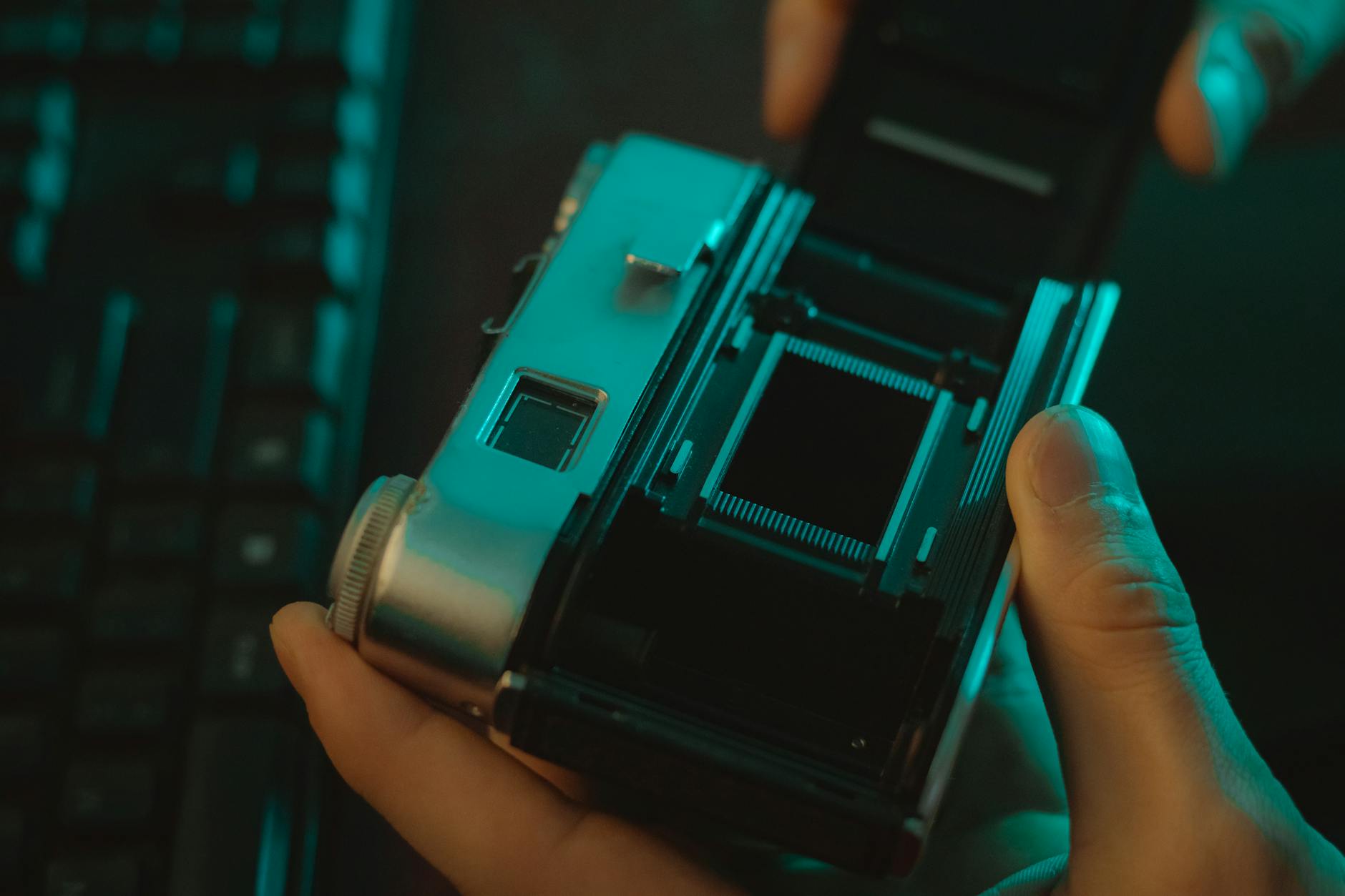 Close-up of vintage film camera being inspected, with focus on film compartment.