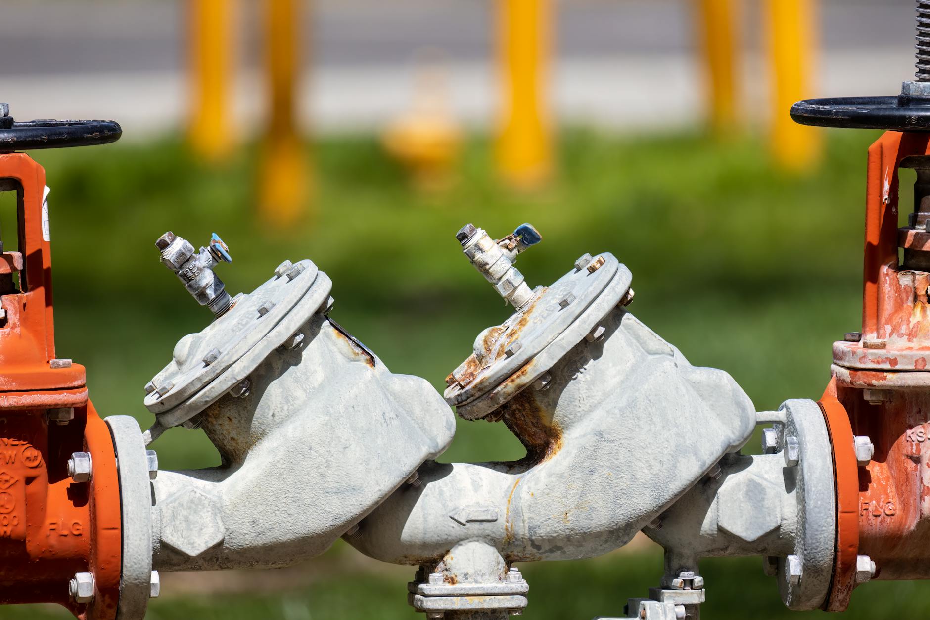 Detailed view of rusted industrial gas valves outdoors on a sunny day.