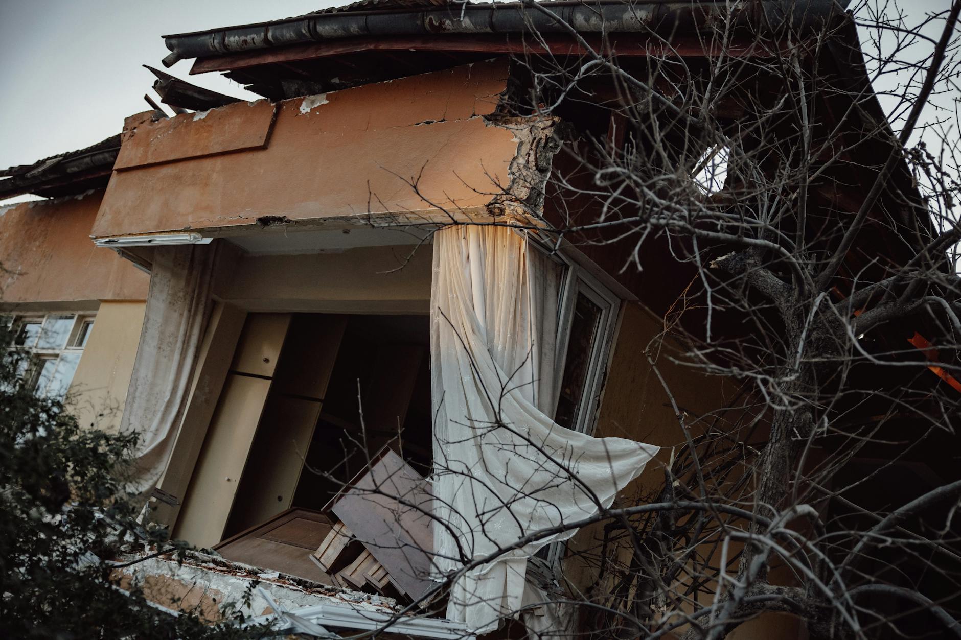 Exterior of a damaged house showing destruction from a natural disaster.