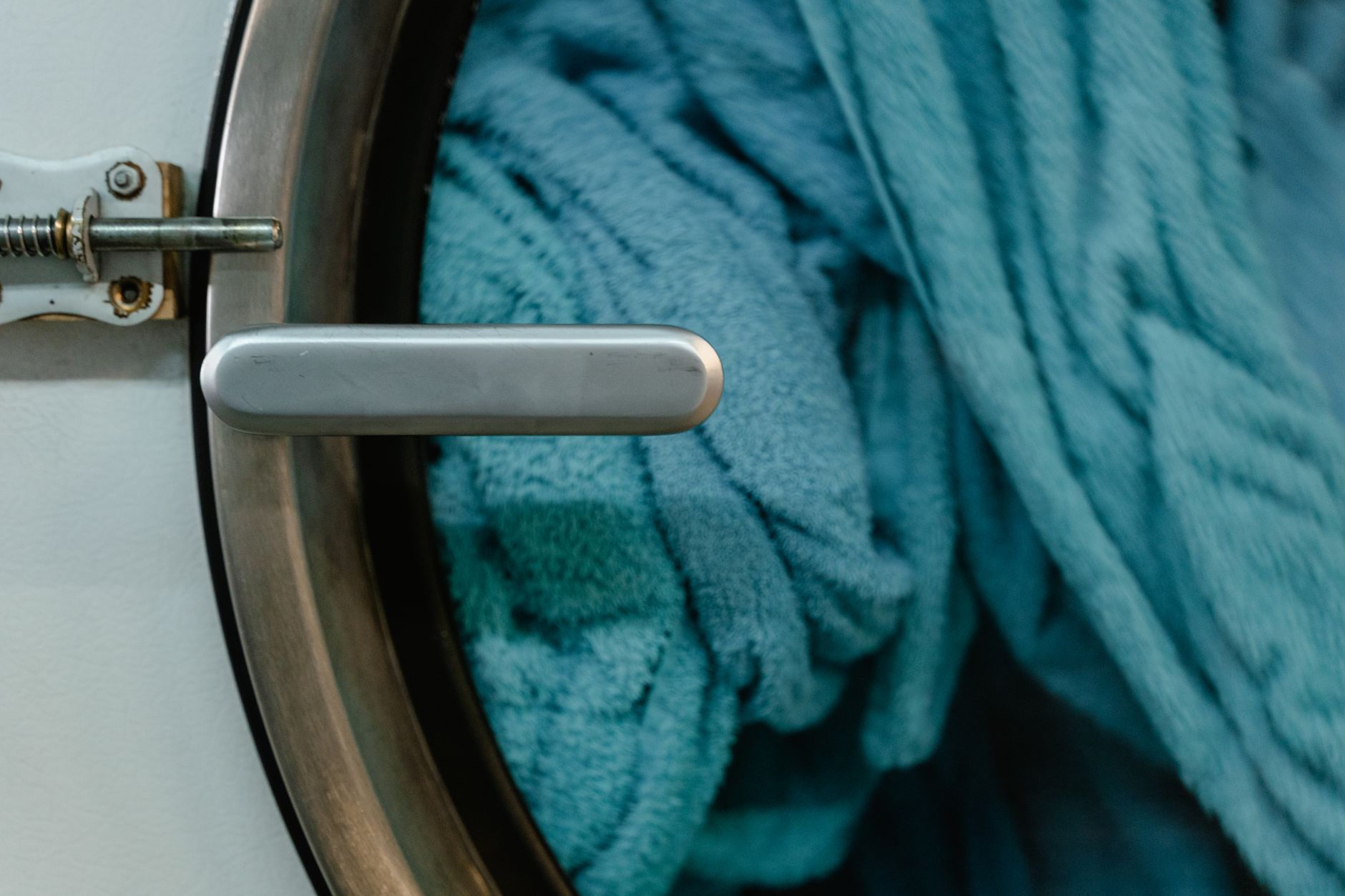 Detailed image of a washing machine door with blue towels inside, focusing on household chores.