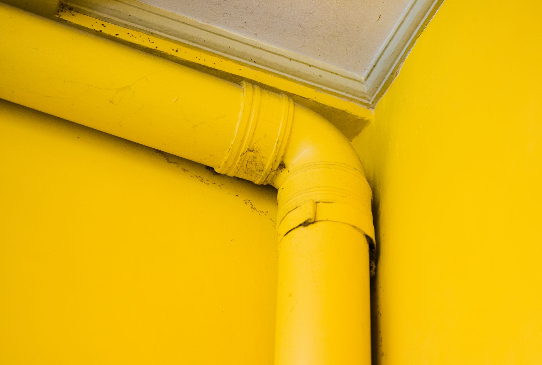 Detailed close-up shot of a yellow pipe in a corner with vibrant color contrast.