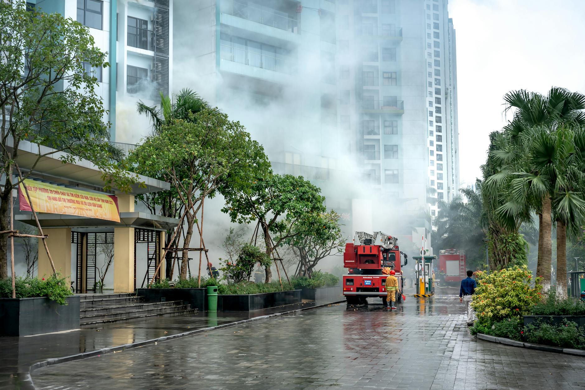Firefighters respond to a building fire, battling smoke in an urban residential area.