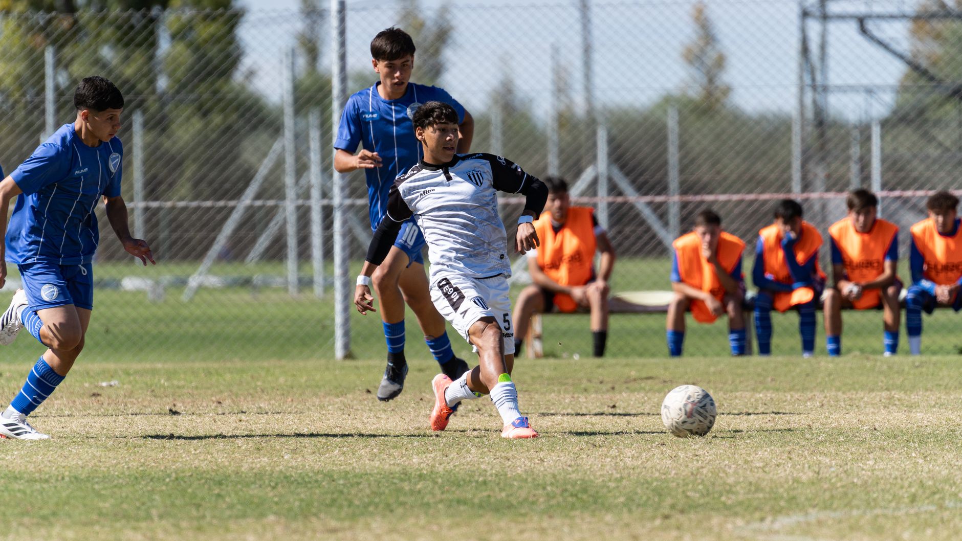 Action-packed capture of youth soccer players competing fiercely on the field during a sunny day.