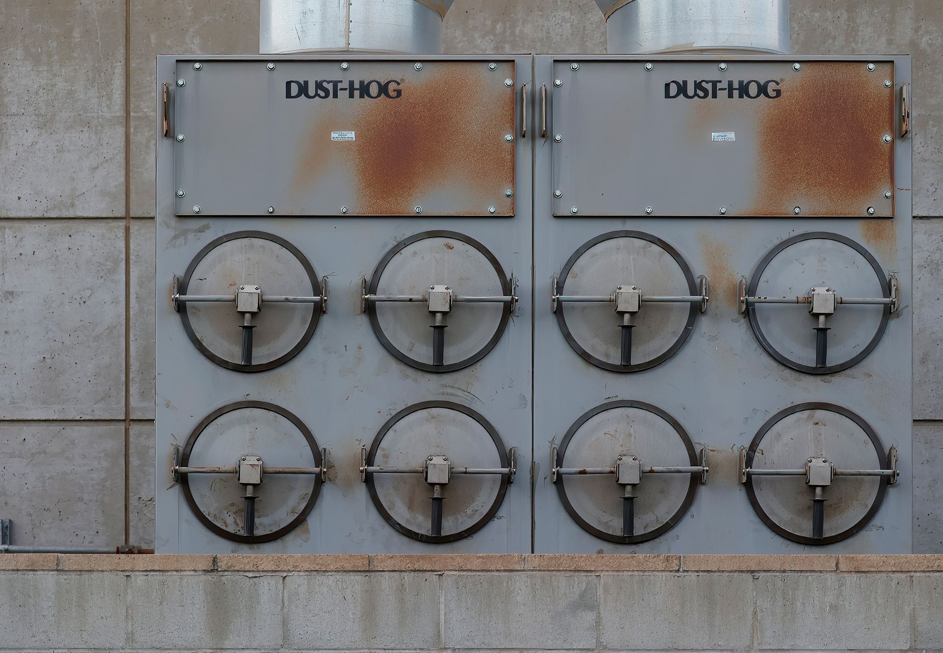 Close-up of a Dust-Hog industrial dust collector with six rusty filtration units.