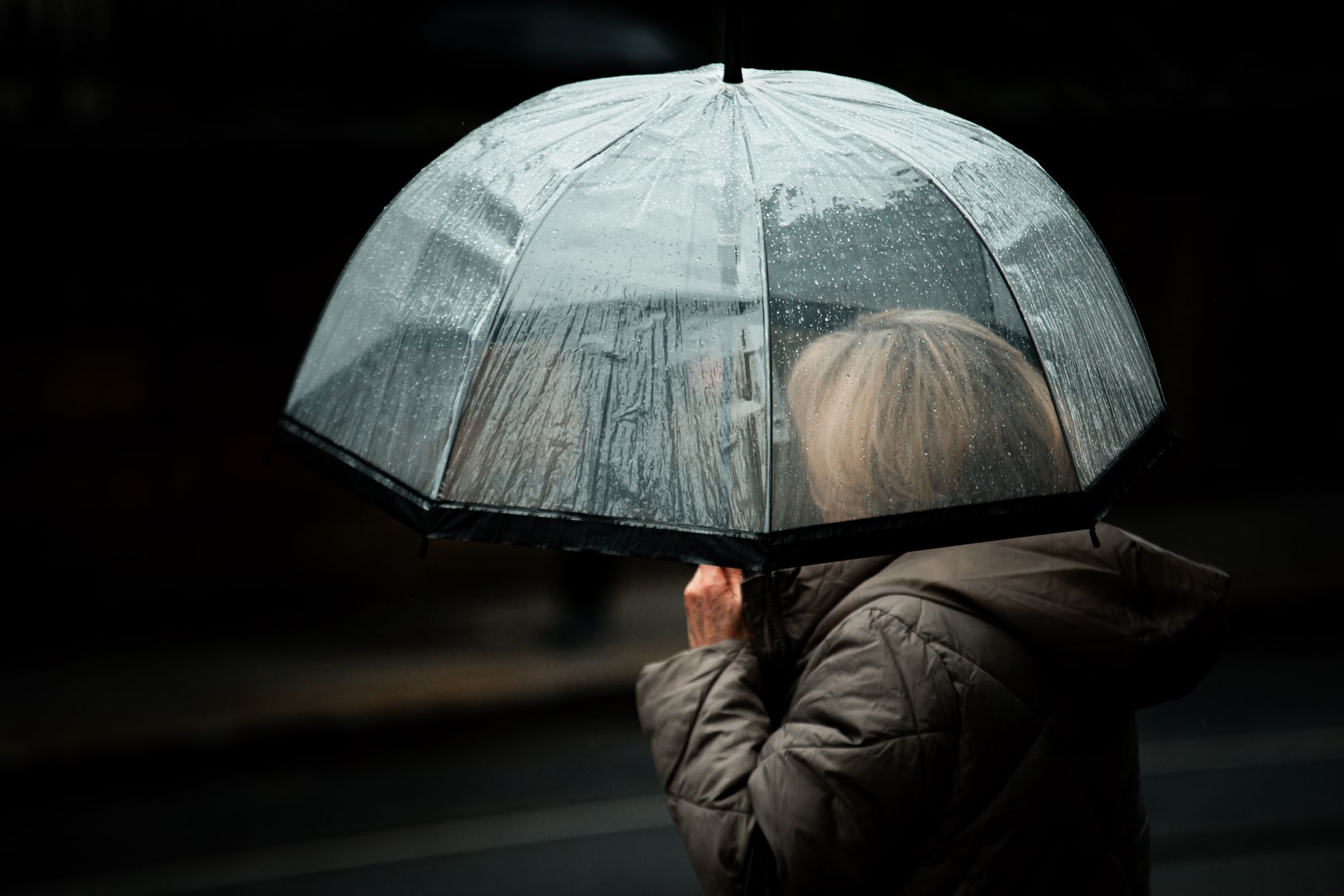 Moody street photography capturing a silhouette with a transparent umbrella in rainy Dublin.