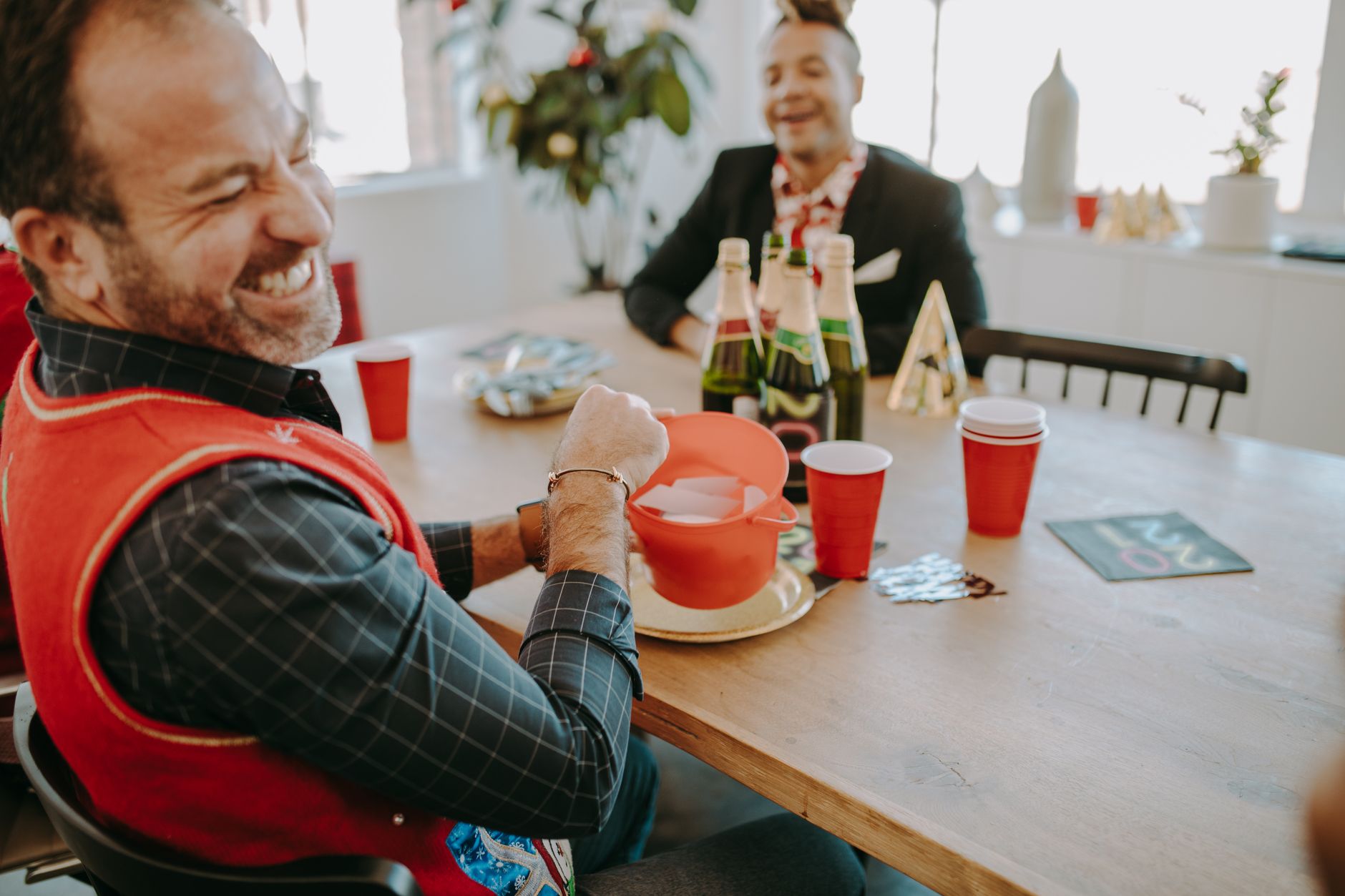 Two adults enjoying a festive celebration indoors, sharing smiles and laughter.