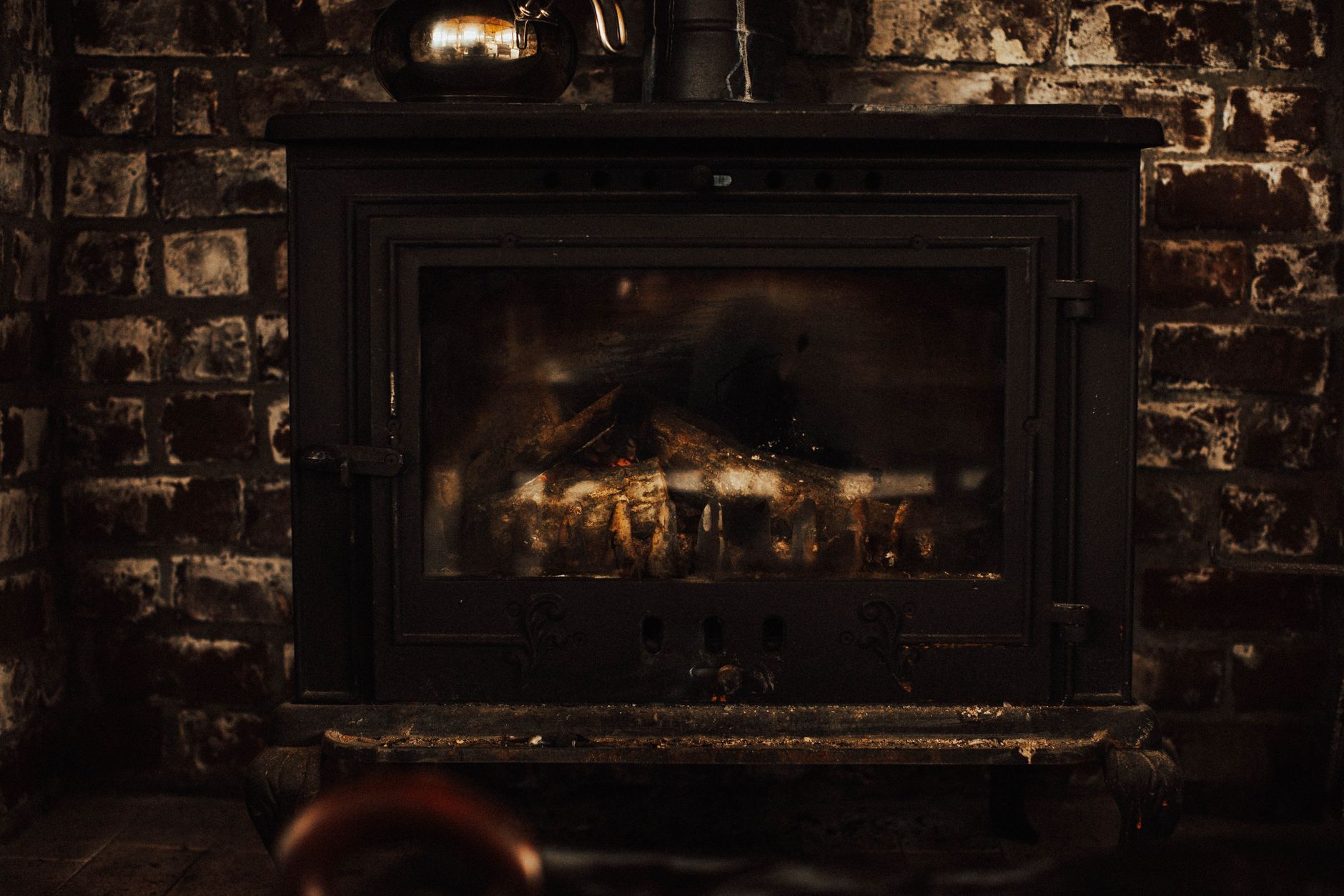 A warm and inviting vintage fireplace against a rustic brick wall, perfect for cozy winter settings.