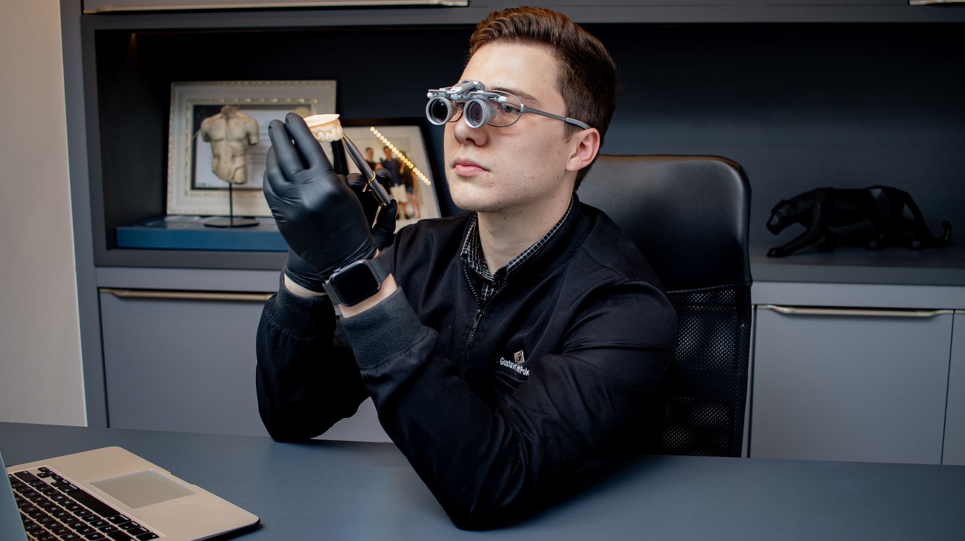 Dentist uses magnifying glasses to examine dental mold in modern office, showcasing professional dental care.