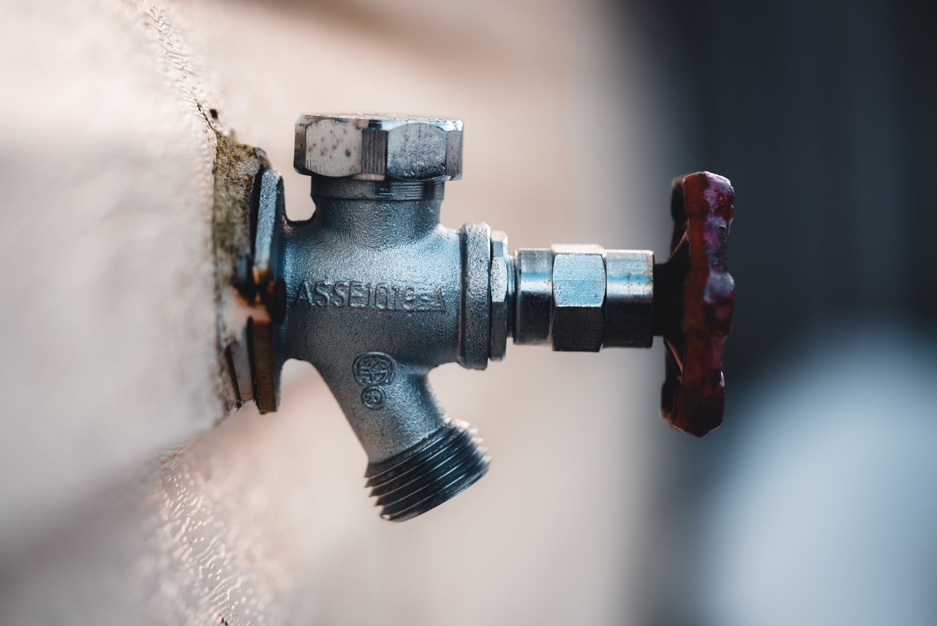 Detailed close-up of a metal faucet mounted on an exterior wall with visible textures.