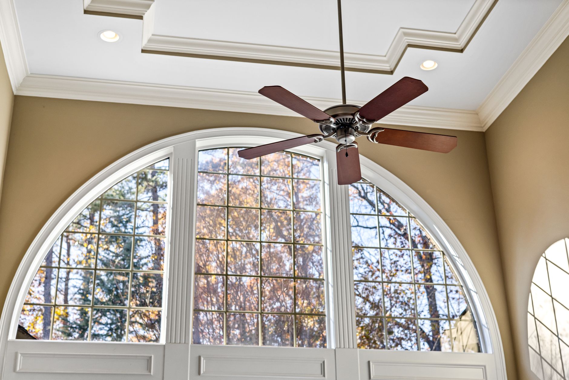 Spacious interior featuring an arched window and decorative ceiling fan with natural light.