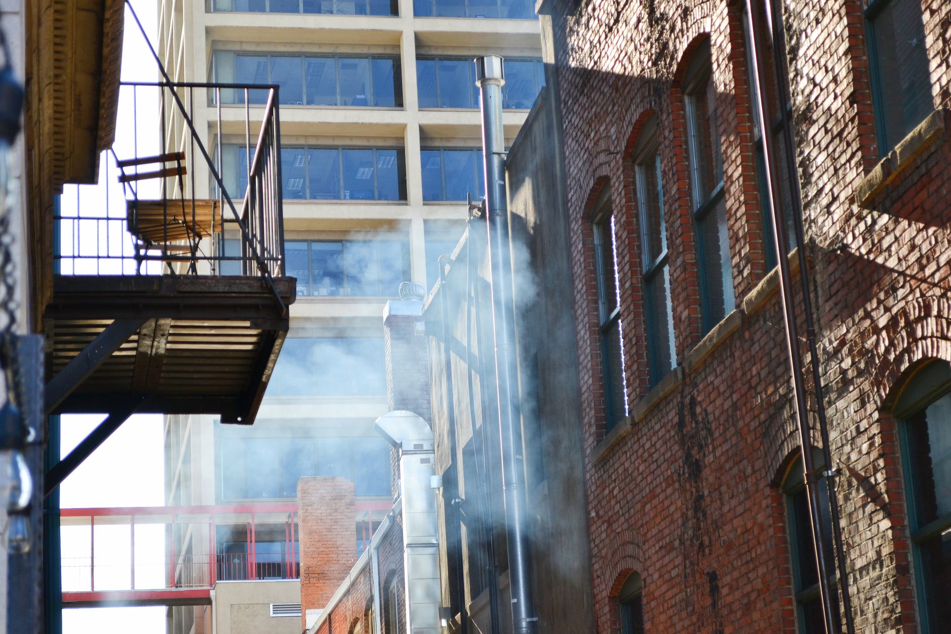 A cityscape showing a balcony and brick buildings emitting smoke, capturing urban architectural vibe.