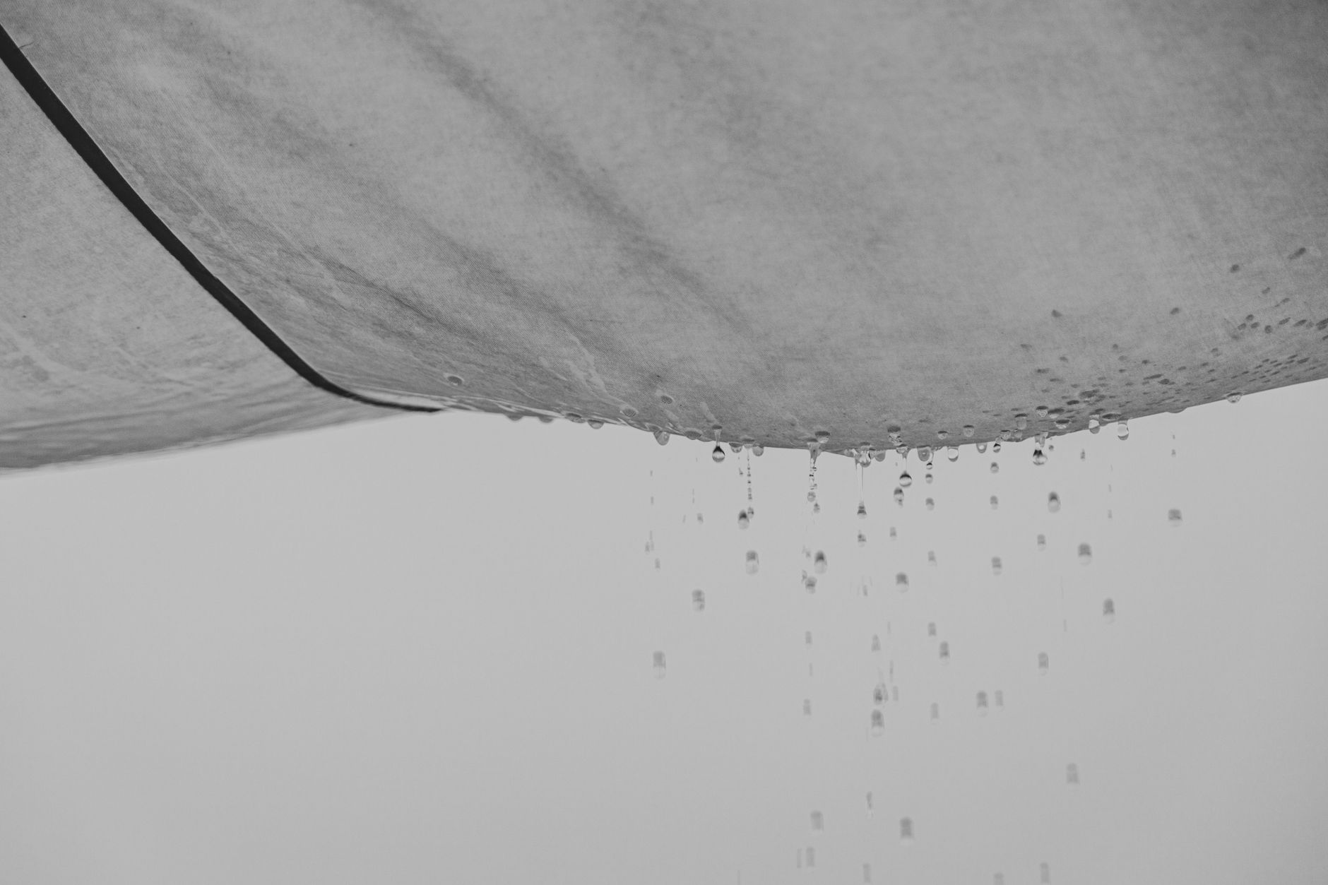 Black and white composition of water drops falling from rag material on gray background