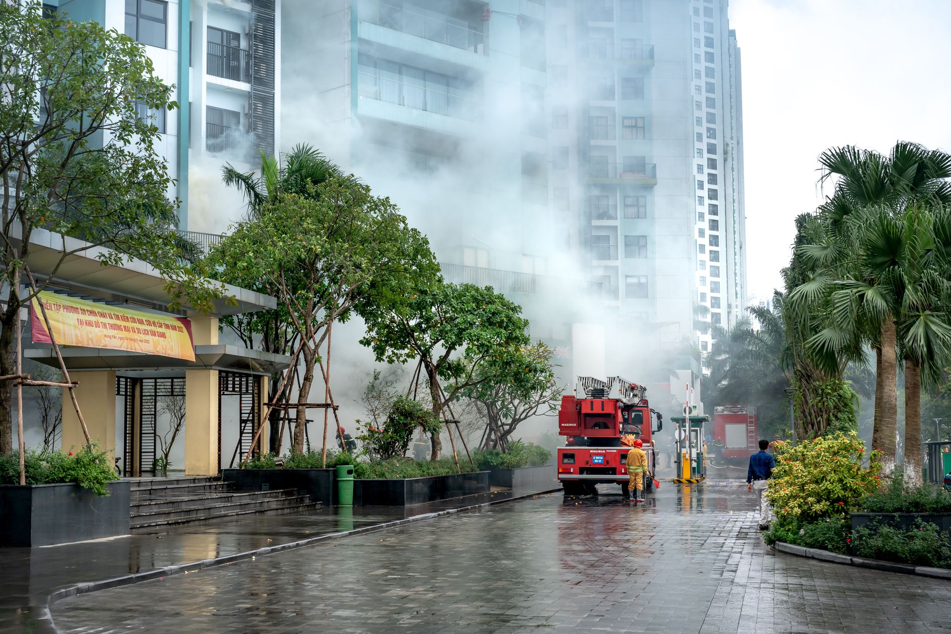 Firefighters respond to a building fire, battling smoke in an urban residential area.