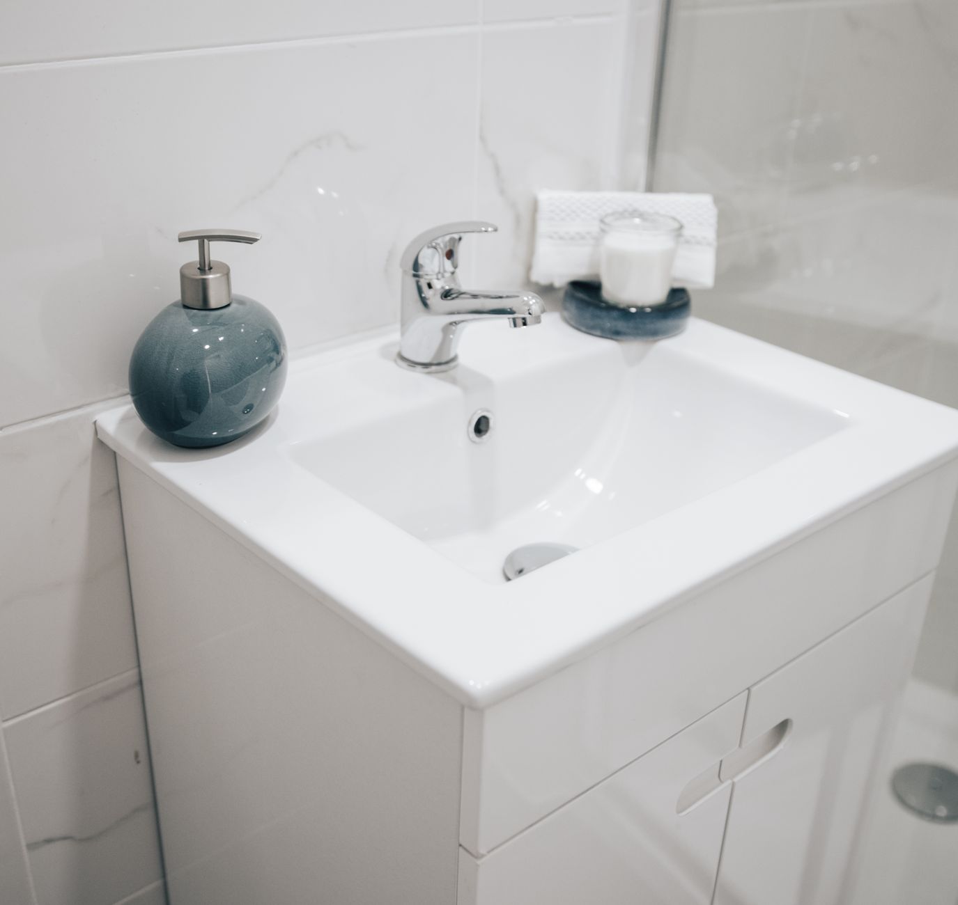 A clean and modern bathroom sink with a chrome faucet, soap dispenser, and towel for a fresh look.
