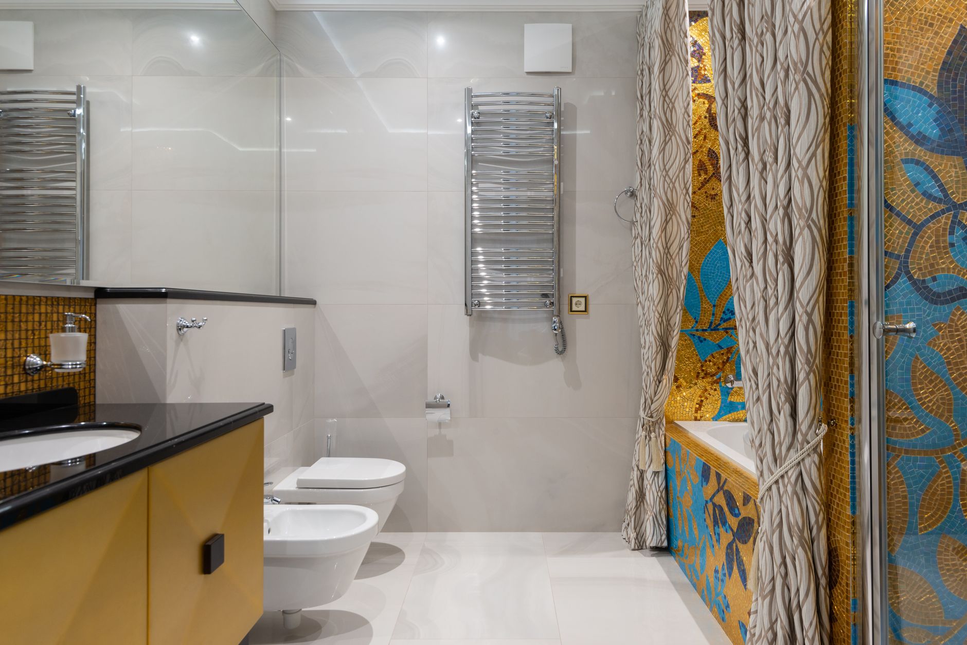 A stylish bathroom featuring a bathtub with colorful mosaic tiles and elegant decor for a luxurious feel.