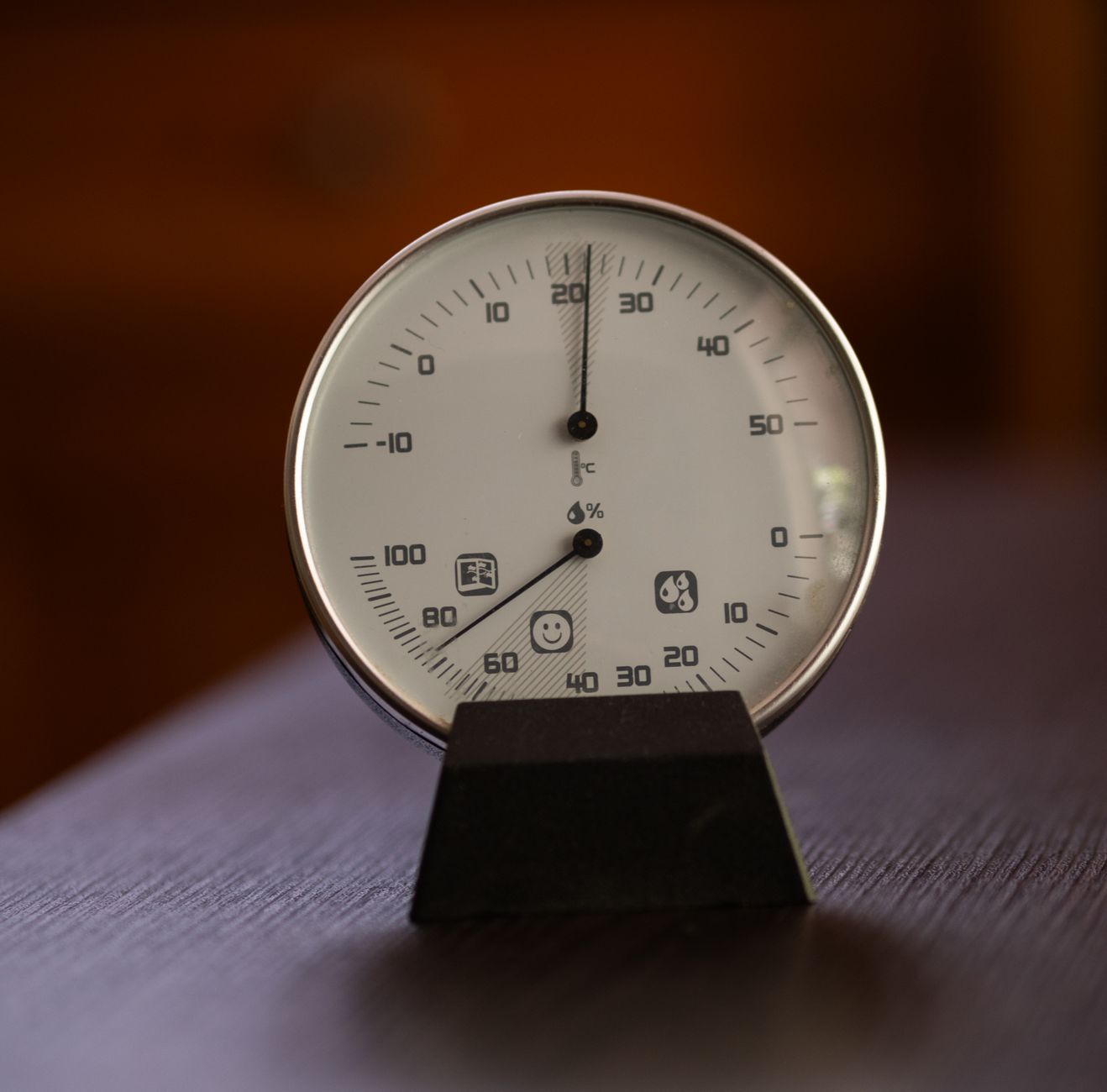 Close-up of an analog hygrometer and thermometer displaying temperature and humidity indoors.
