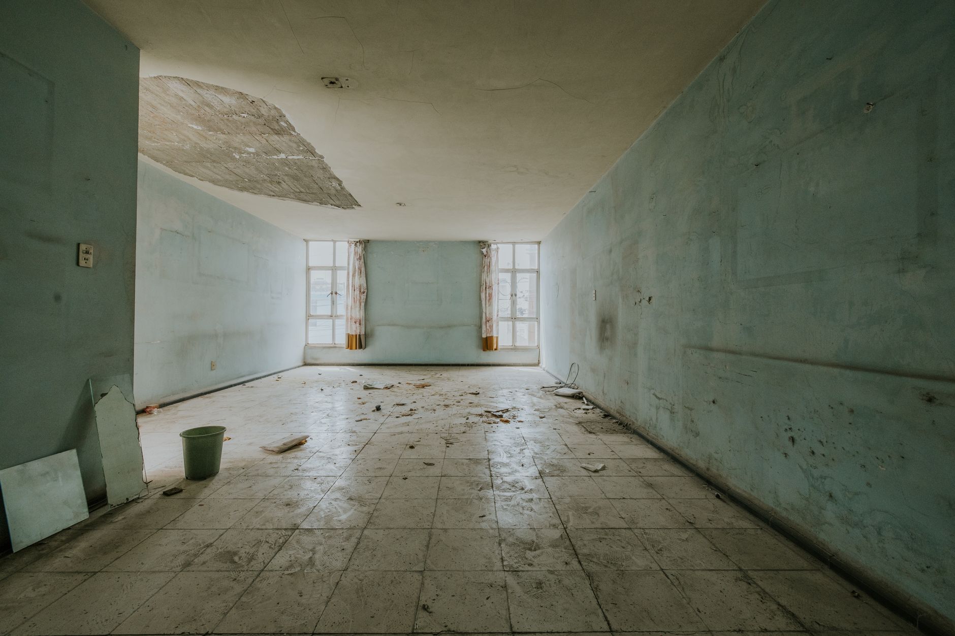 Explore an abandoned room with peeling paint and debris, showing decay.