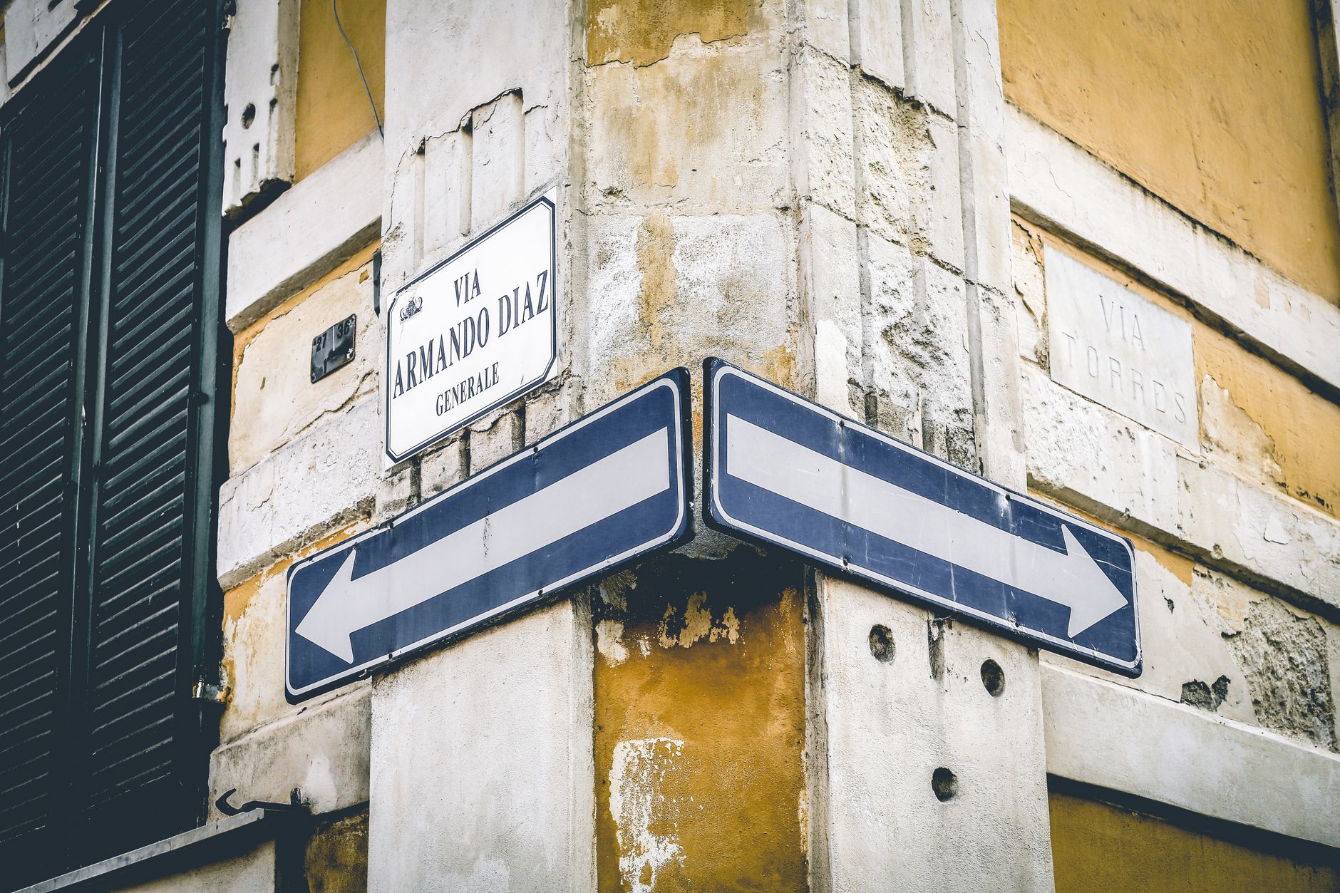 A rustic urban corner with directional signs and vintage architecture.