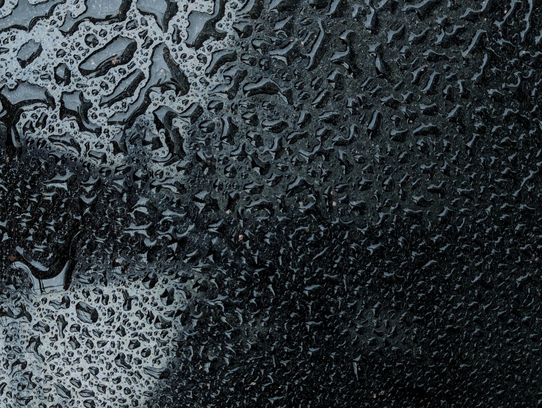 Raindrops creating intricate patterns on a dark background, photographed in Dhaka, Bangladesh.