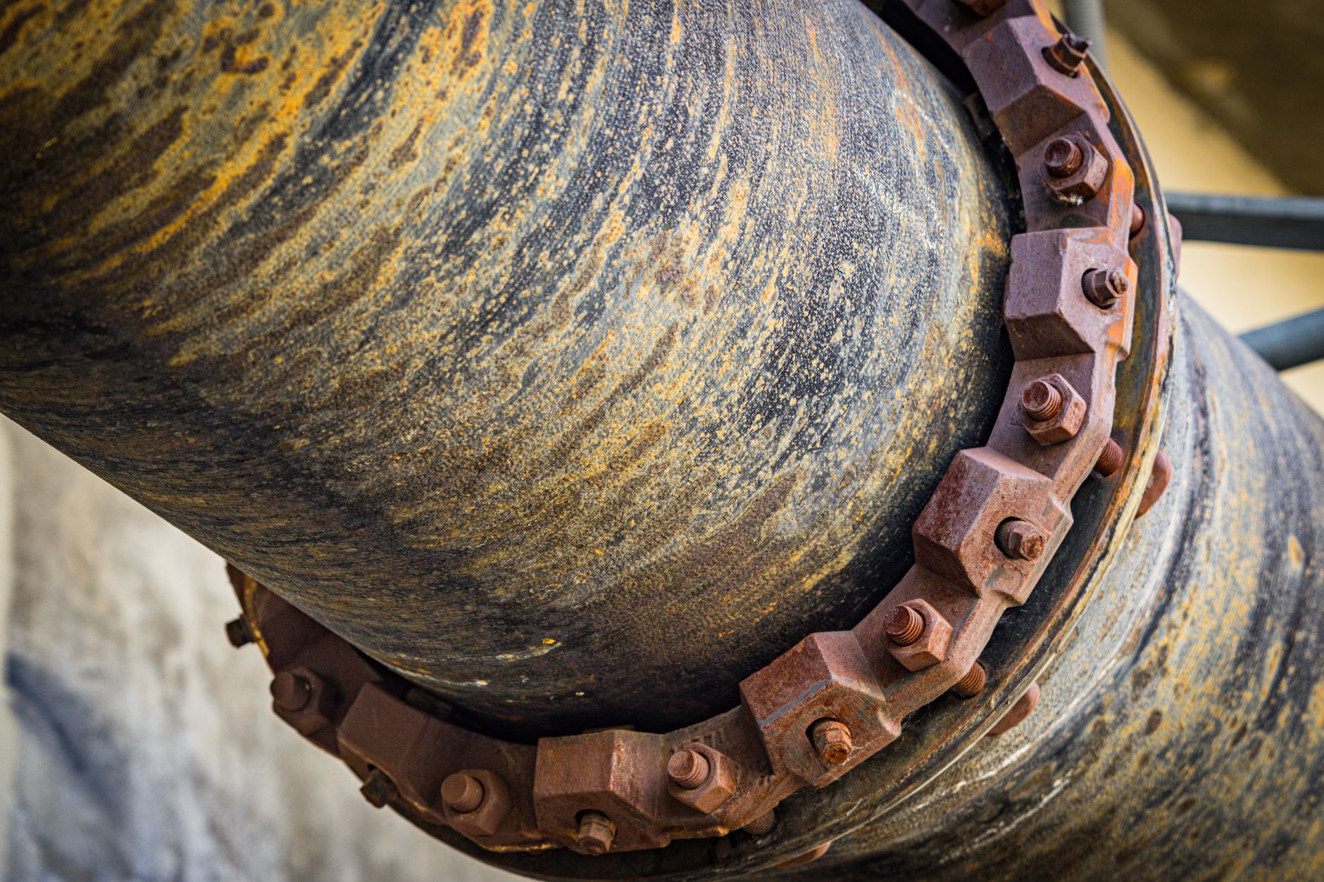 A detailed close-up of a large rusty industrial pipe with bolts, showcasing texture.