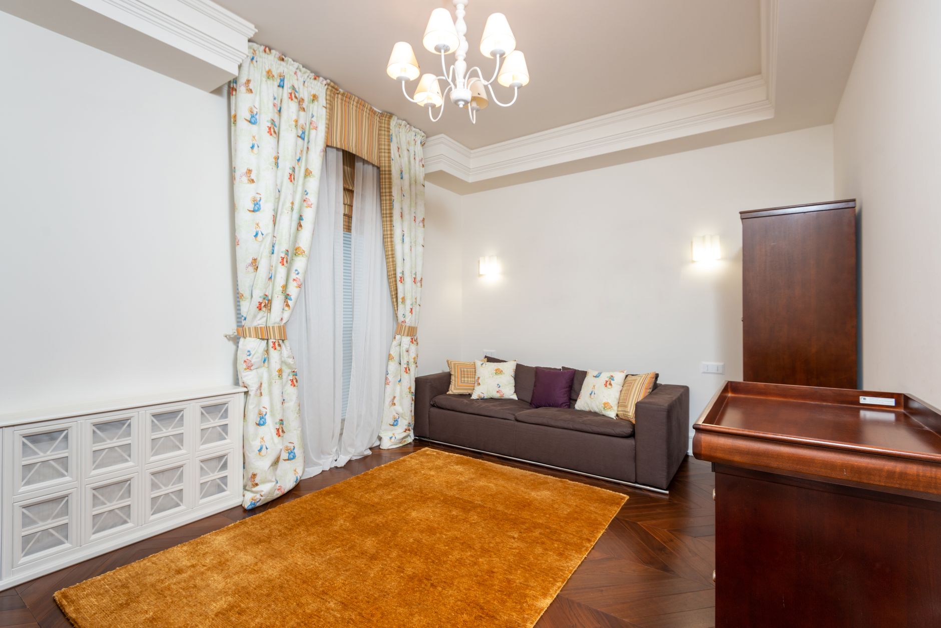 Bright and spacious living room featuring elegant chandelier, cozy sofa, and tasteful decor for a stylish ambiance.