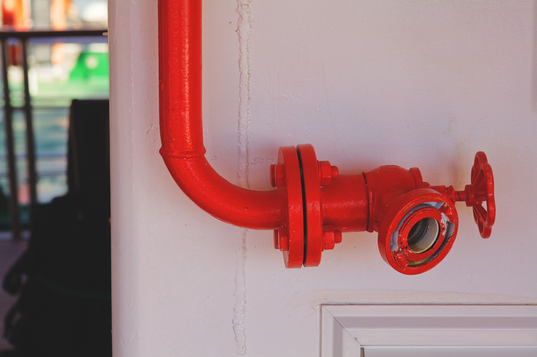 Close-up of a vibrant red fire safety valve attached to a white wall.