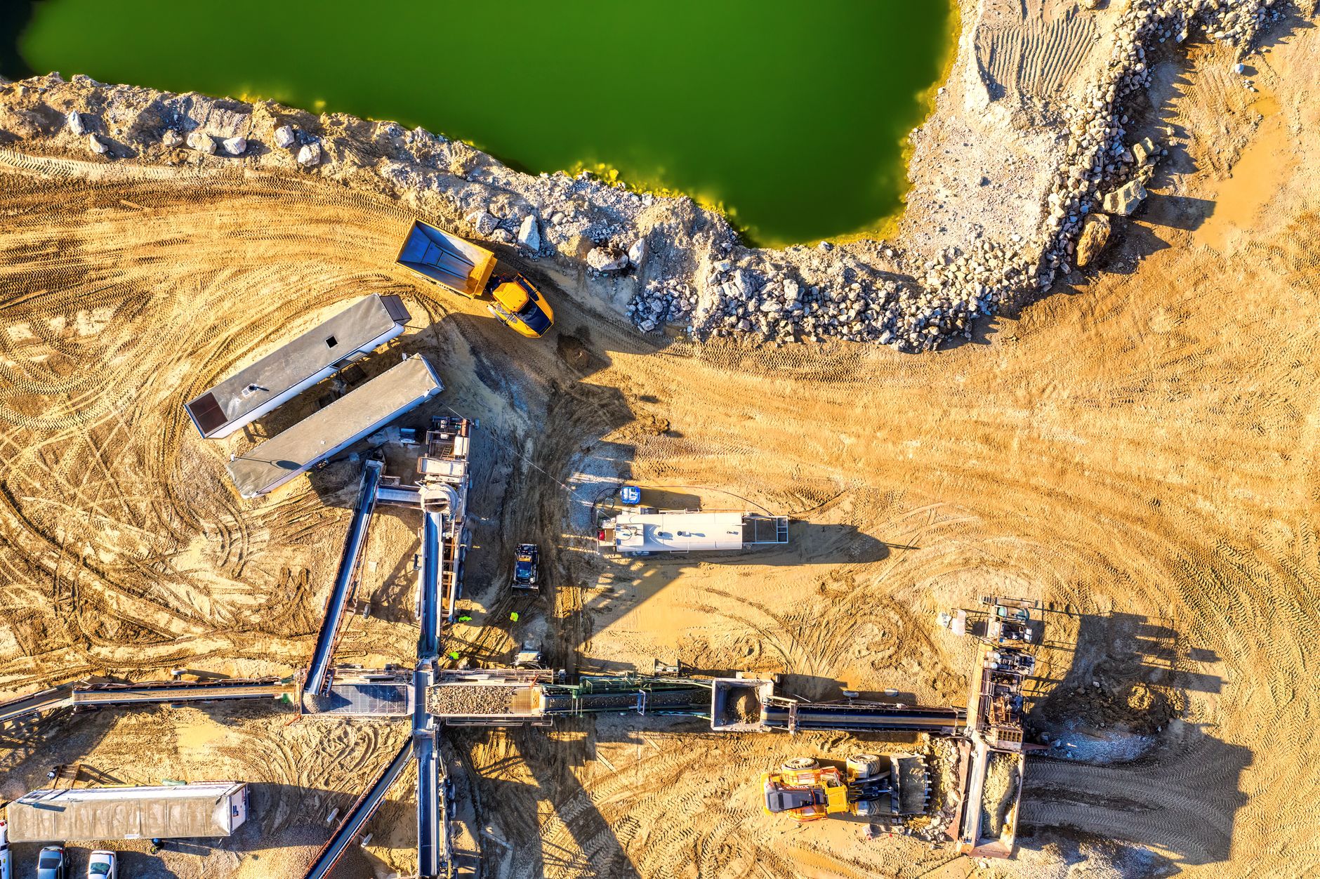 High-resolution aerial image of construction site with heavy machinery and a green water body in Rochester, MN.