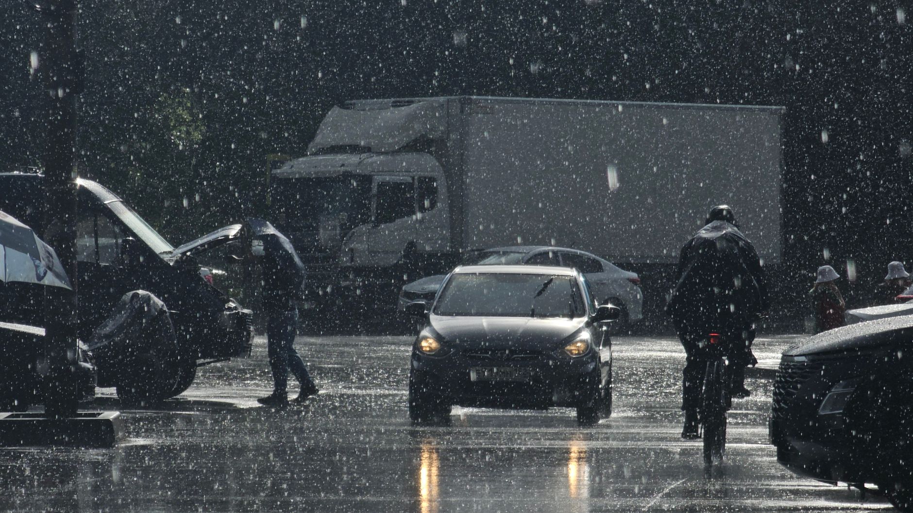 Moody urban street scene in heavy rain with cars and pedestrians.