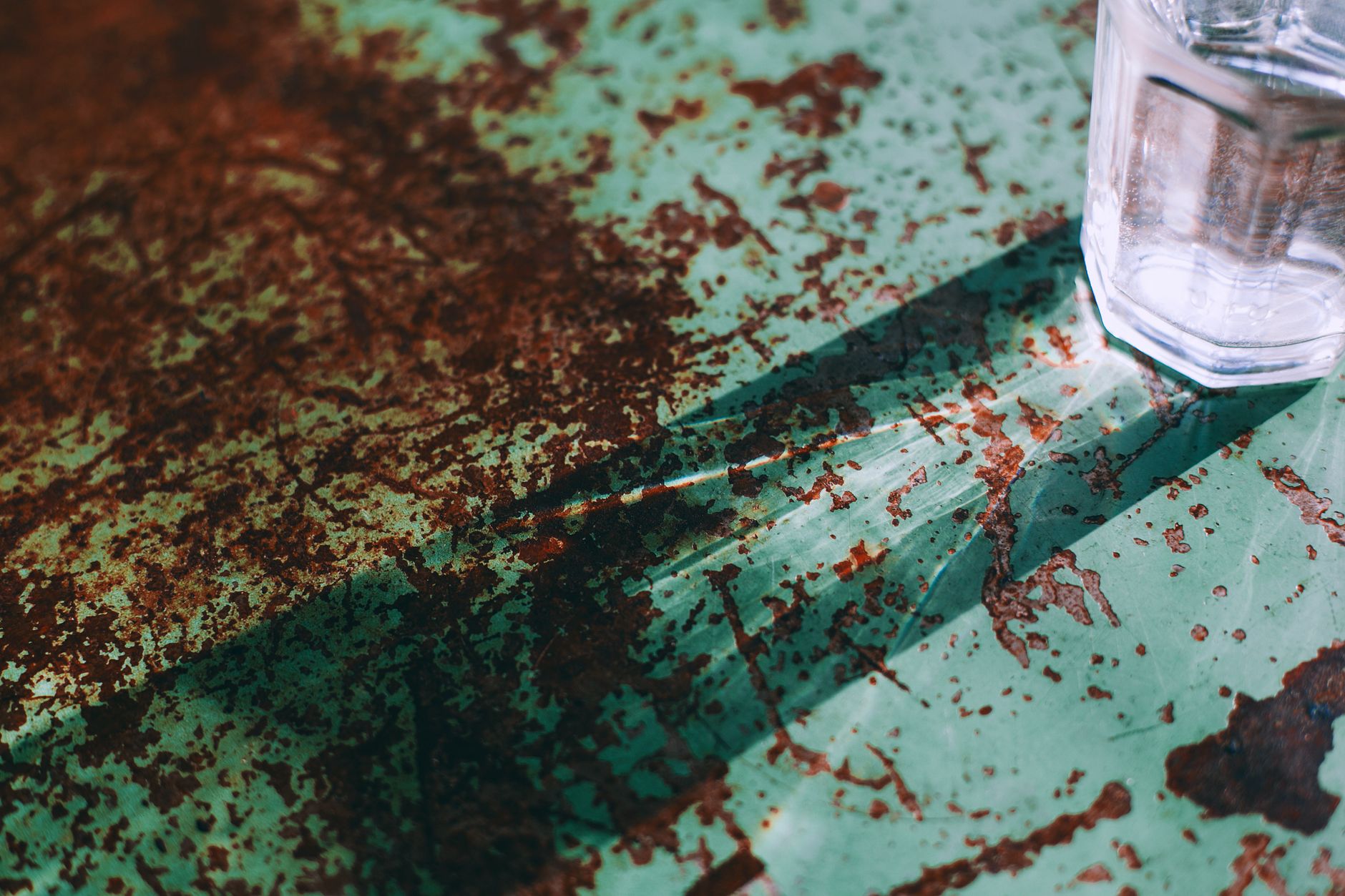 From above of crystal transparent glass of water placed on damaged rusty metal surface with scratches