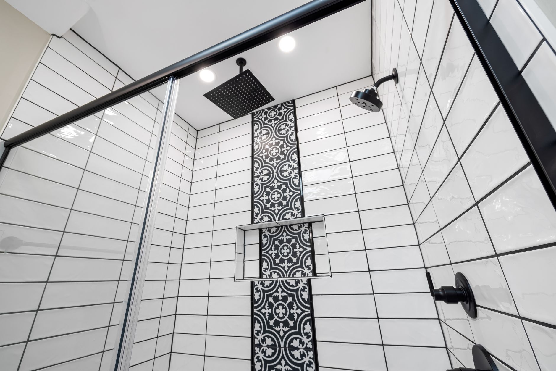 Stylish bathroom with a modern shower featuring a patterned tiled wall and black fixtures.
