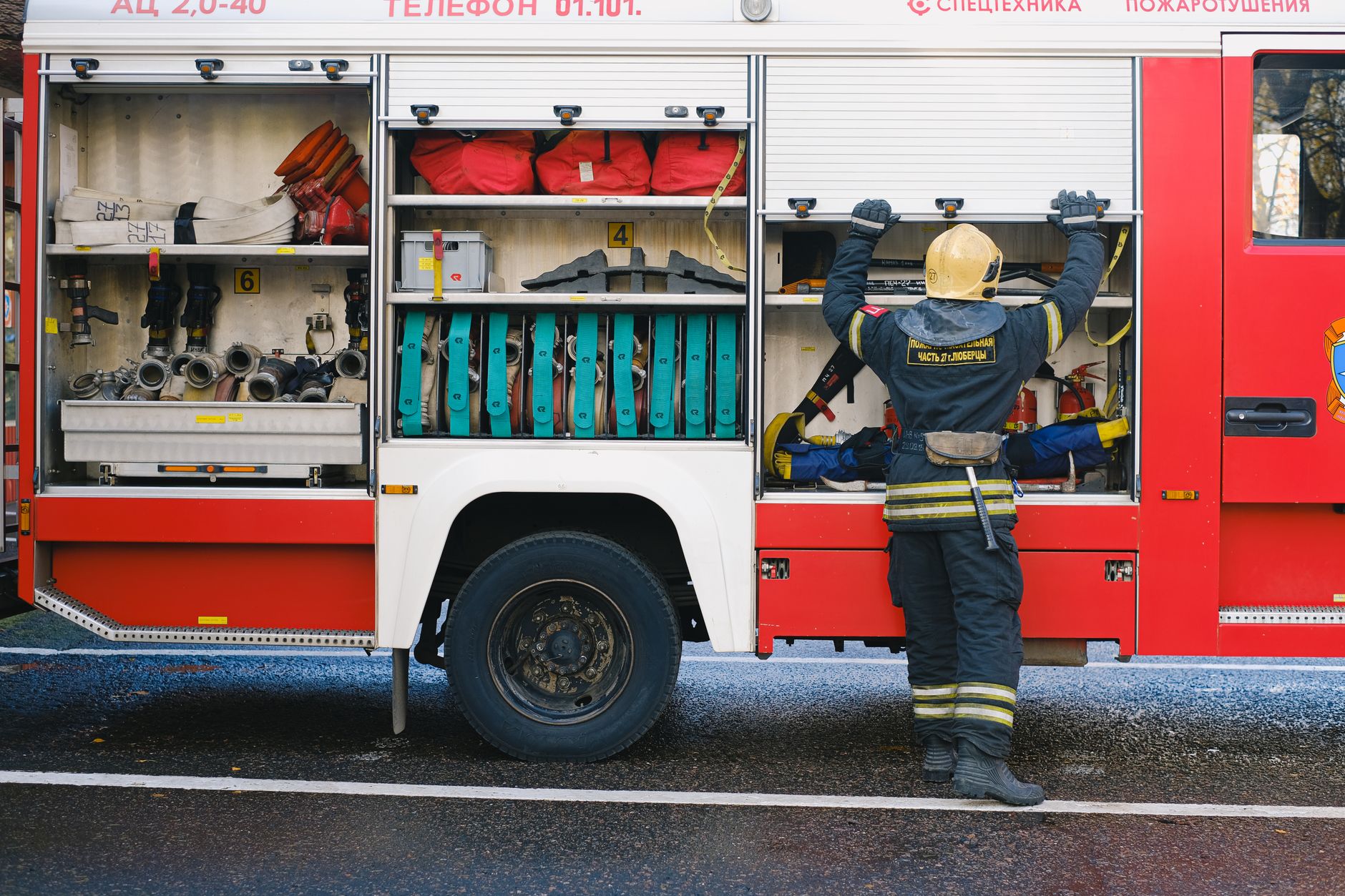 A dedicated firefighter organizing essential equipment on the side of a fire truck.