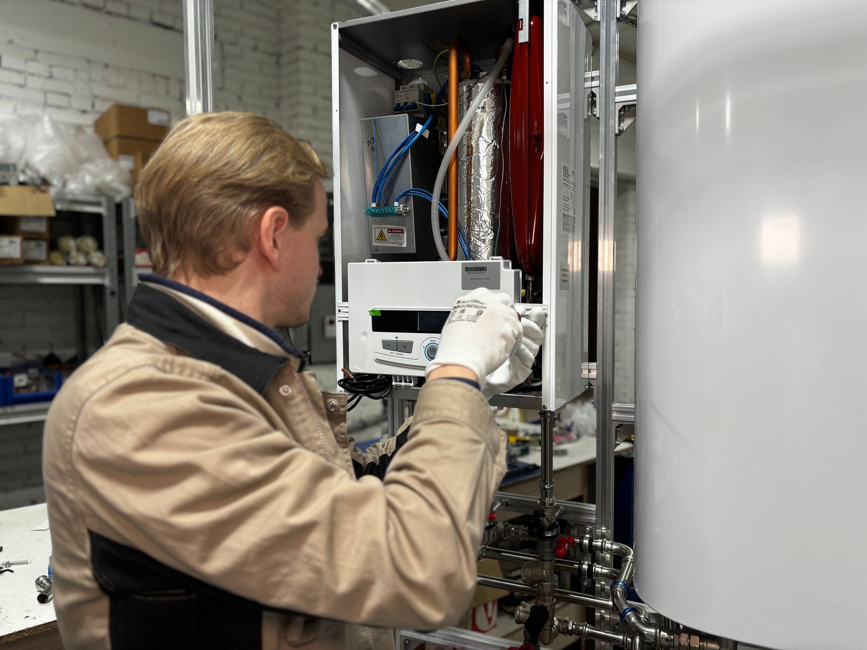 Technician installing or repairing a heating system in an indoor workshop setting.