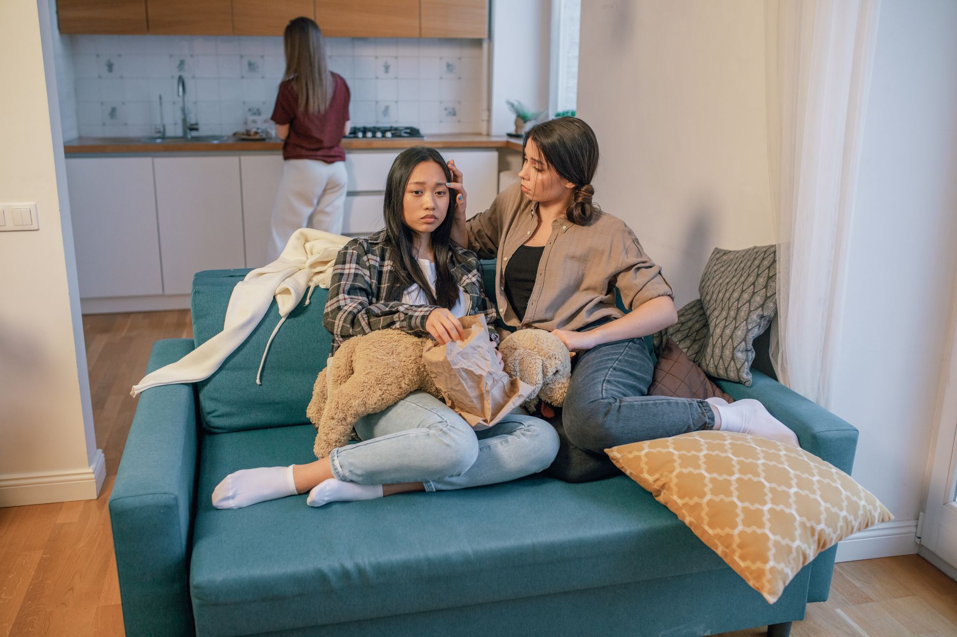 Two women comforting each other on a sofa. Scene reflects support and friendship.